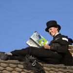 Schornsteinfeger liest Gutschein auf Dach 